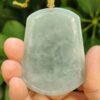 a hand holding a jade pendant
