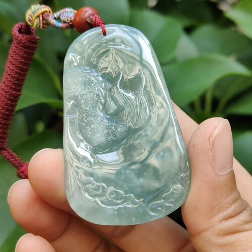 une main tenant un pendentif en jade