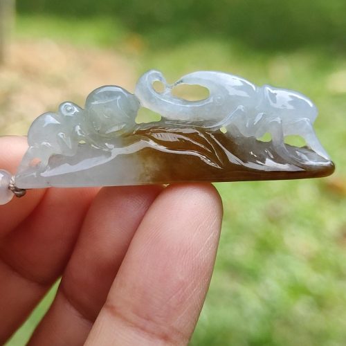 a hand holding a jade pendant