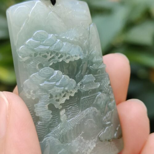 a hand holding a jade pendant