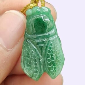 a hand holding a green stone insect pendant
