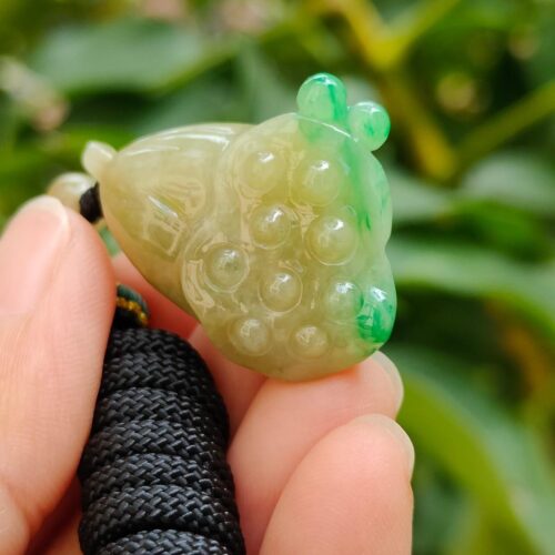 ஜேட் தவளை பதக்கத்தை வைத்திருக்கும் ஒரு கை