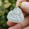 une main tenant un pendentif de Bouddha en jade