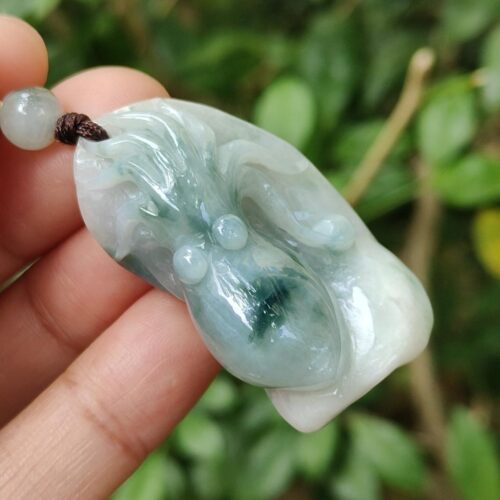 a hand holding a jade pendant
