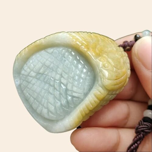 a hand holding a jade pendant