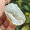 a hand holding a jade pendant