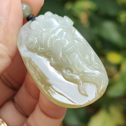 a hand holding a jade pendant