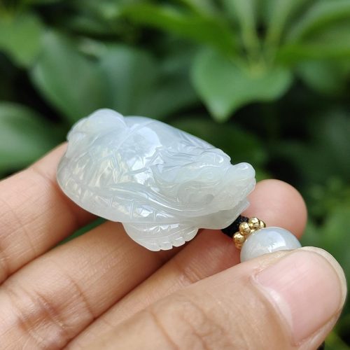 tangan memegang liontin giok