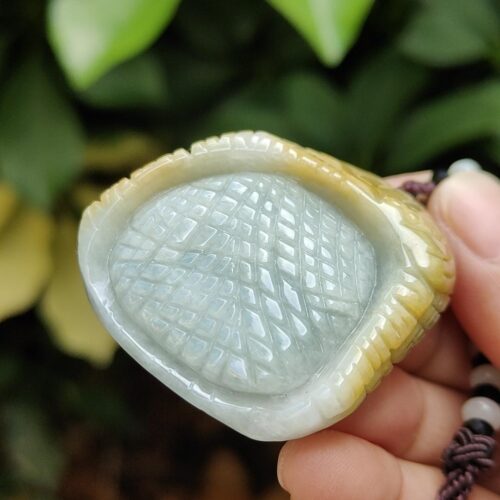 a hand holding a jade pendant