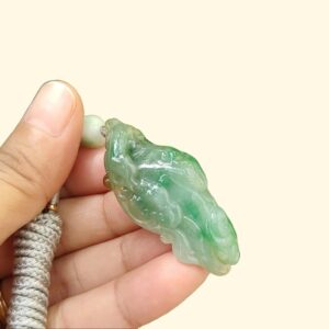 a hand holding a jade pendant