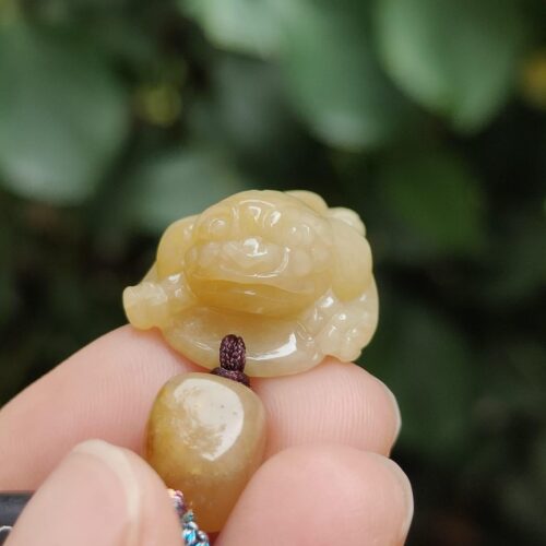 a hand holding a small jade frog