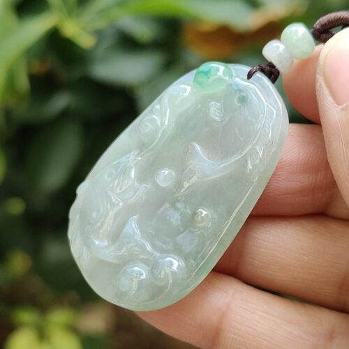 a hand holding a jade pendant