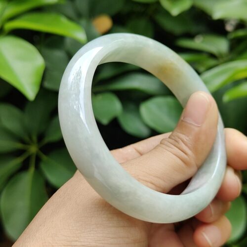 a hand holding a white circular bracelet