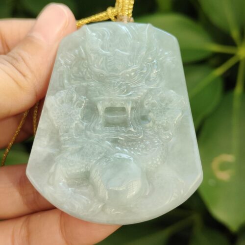 a hand holding a jade pendant