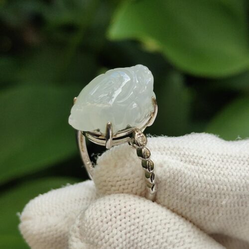 a hand wearing a glove holding a white ring