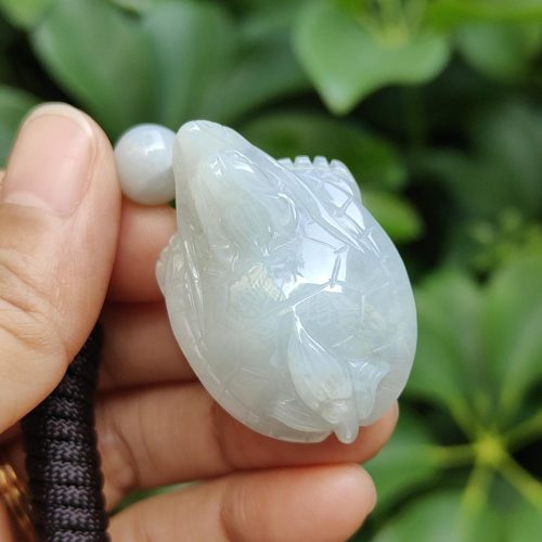 tangan memegang liontin giok