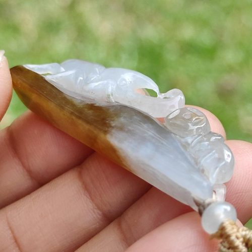 a hand holding a jade pendant