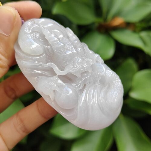 a hand holding a white jade pendant