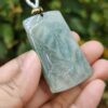 a hand holding a jade pendant