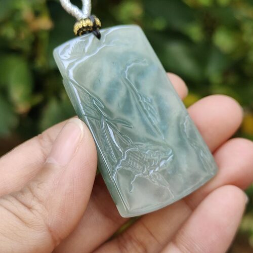 a hand holding a jade pendant