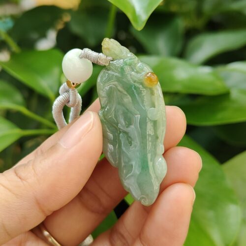 une main tenant un pendentif en jade