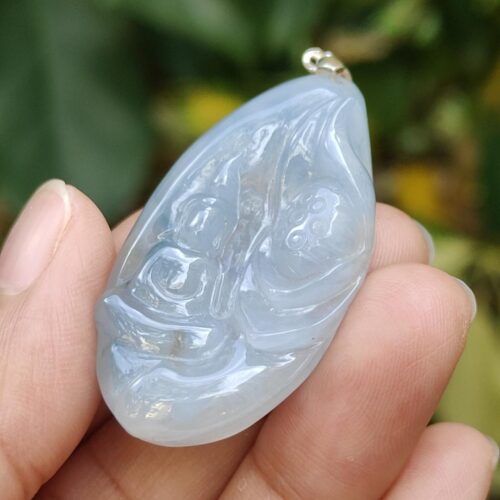 a hand holding a blue stone pendant