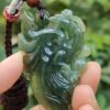 a hand holding a jade pendant