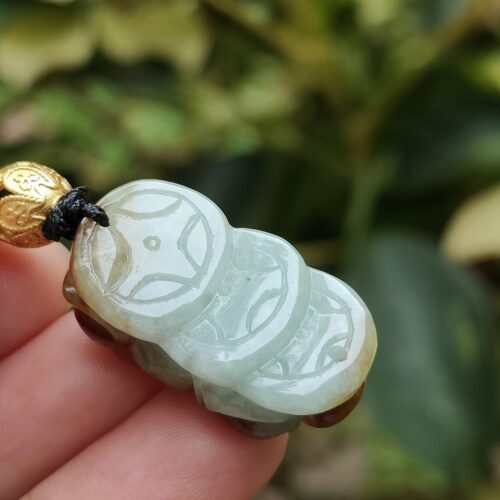 uma mão segurando um pingente de jade