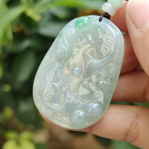 a hand holding a jade pendant