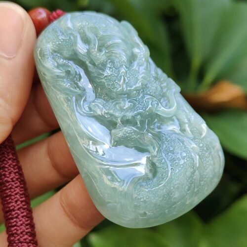 une main tenant un pendentif en jade