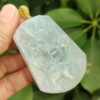a hand holding a jade pendant
