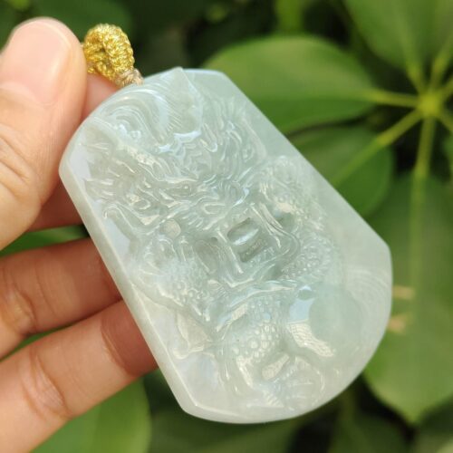 a hand holding a jade pendant