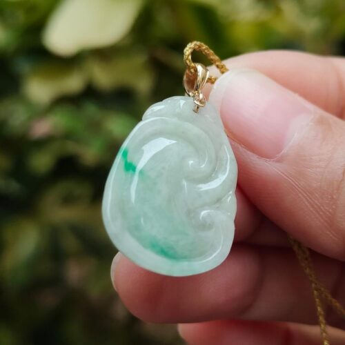 a hand holding a jade pendant