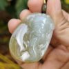 a hand holding a jade pendant