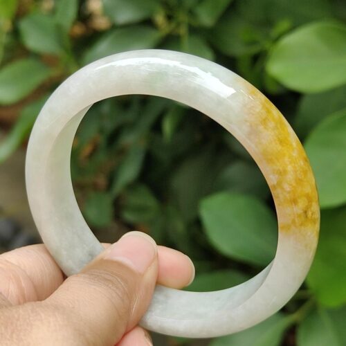 a hand holding a white and yellow bracelet