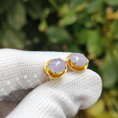 a pair of earrings on a gloved hand