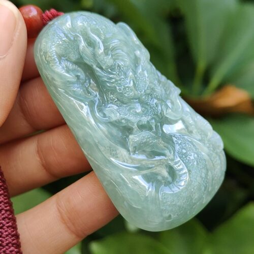 une main tenant un pendentif en jade