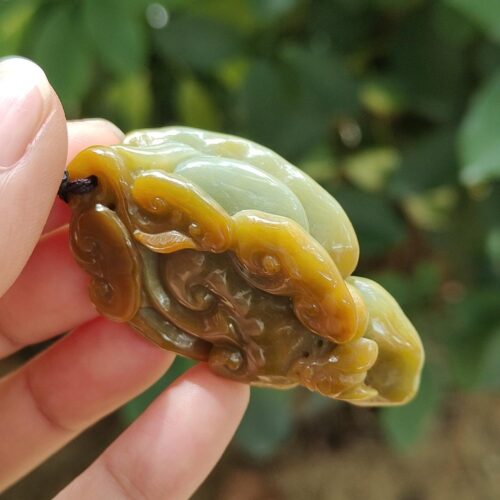 une main tenant un pendentif en jade