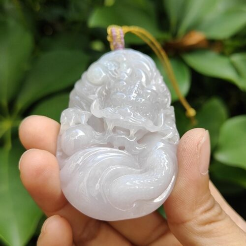 a hand holding a jade pendant