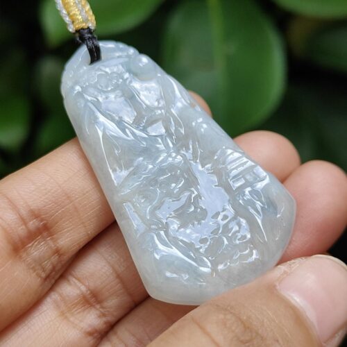 une main tenant un pendentif en jade