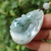 a hand holding a jade pendant