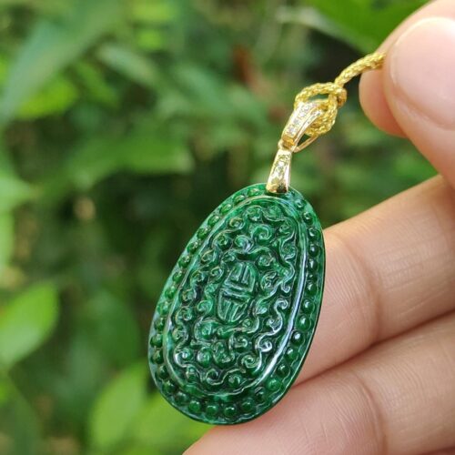 a hand holding a green pendant