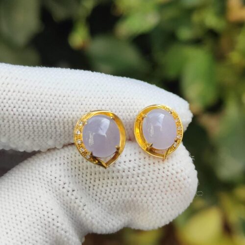 a pair of earrings on a gloved hand