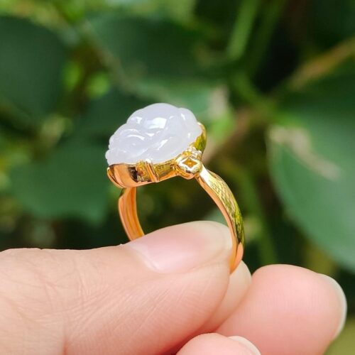 a person holding a gold ring with a carved stone in it