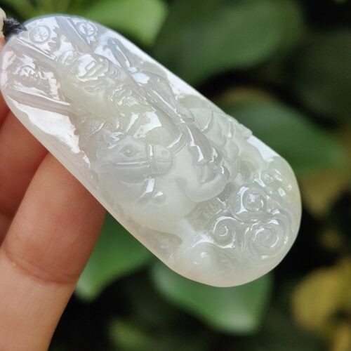 Una mano sosteniendo un colgante de jade blanco.