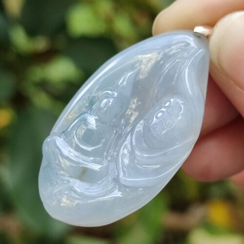 a hand holding a jade pendant
