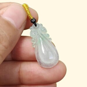 a hand holding a jade pendant