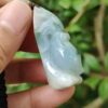a hand holding a jade pendant
