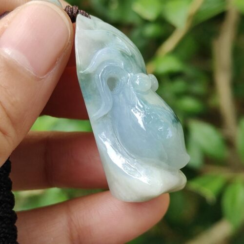 a hand holding a jade pendant