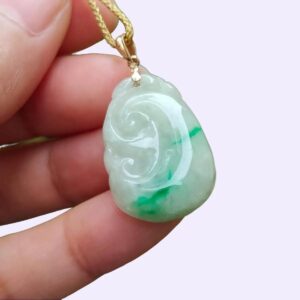 a hand holding a jade pendant